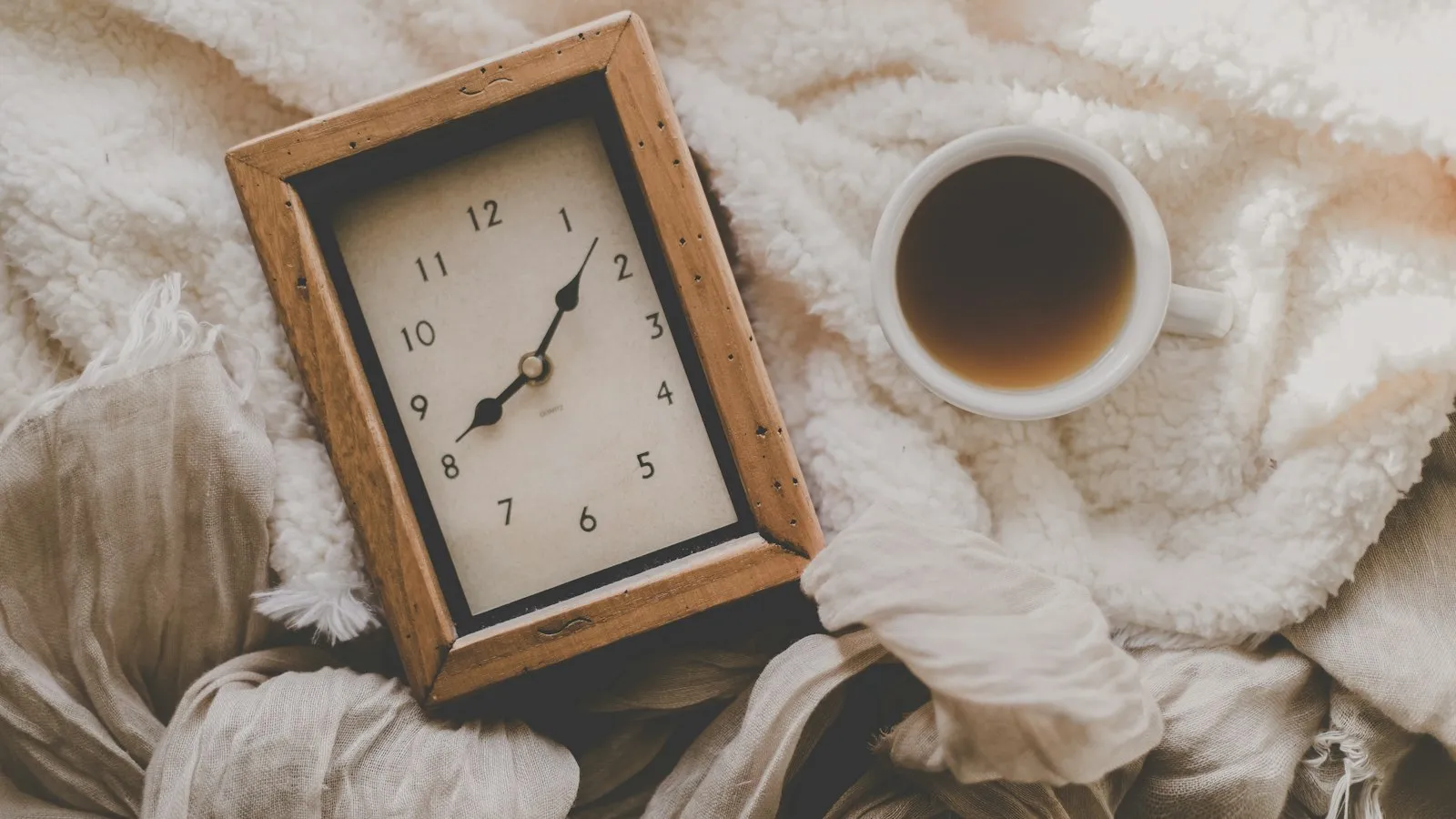 A cup of coffee beside a clock showing the start of a morning shift